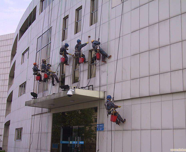 青岛保洁公司作业时，屋顶和地面都有人监护，并用步话机保持联系
