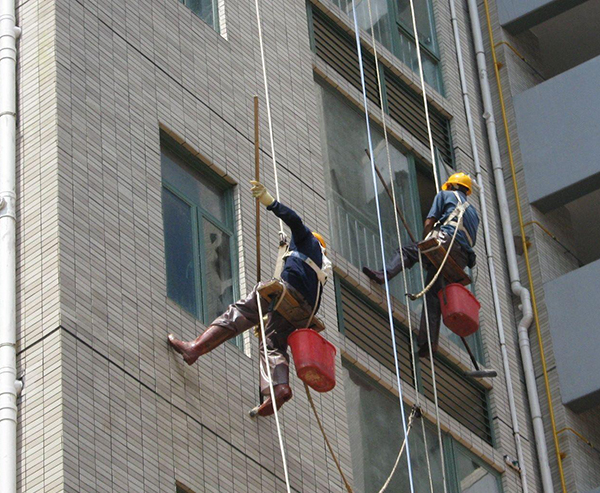 青岛保洁公司作业时，屋顶和地面都有人监护，并用步话机保持联系